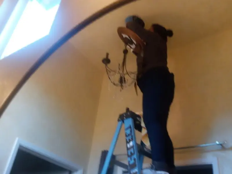Electrician installing a chandelier in a McSwain residence